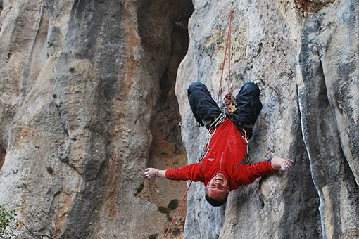 A large image of a climber hanging upside down on a rope