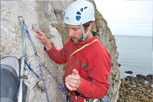 A small image of a climber threading ropes at the top of a cliff