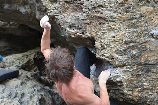 A large image of a climber making a difficult move on a boulder