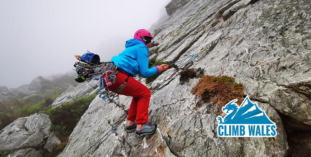 A young woman jumping up and down on the end of a rope whilst trying to see if she can rip some climbing gear out of a crack in the rock