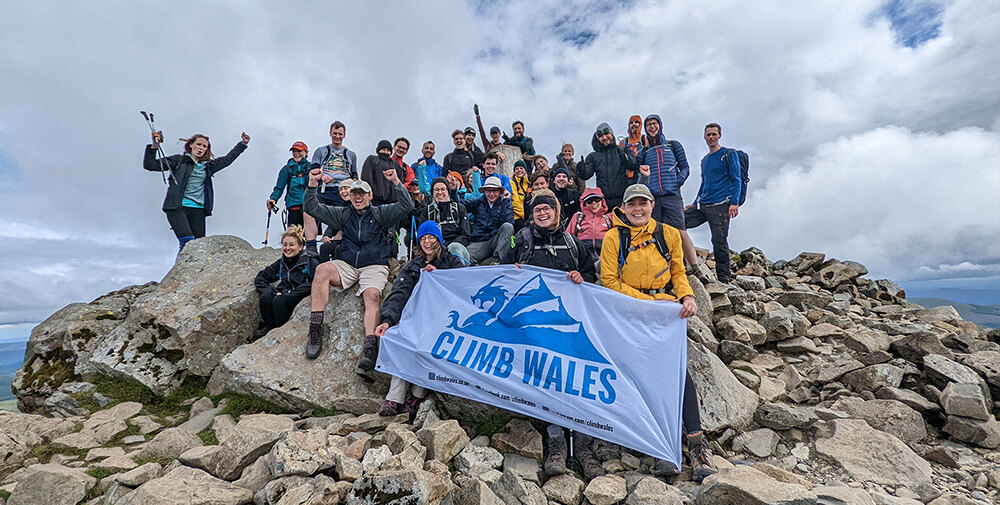 The Corporate Team from Forsters LLP holding a Clibm Wales flag at the summit of Cadair Idris during a Welsh 3 Peaks Challenge