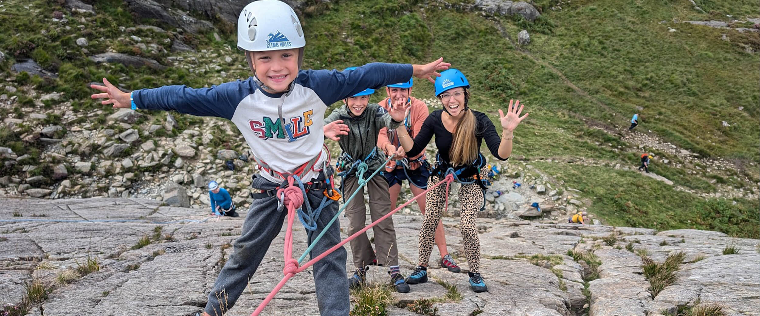 Mum, Dad, and their two boys hanging from a rope during a rock climb
