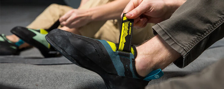 Two rock climbers strapping up their climbing shoes